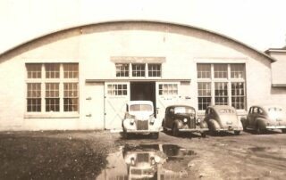 Exterior of the Mapleton Hemp Plant in the 1930s with cars in front of the building.