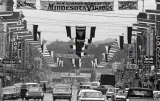 Vikings Training Camp banner on Front Street with cars, black and white image
